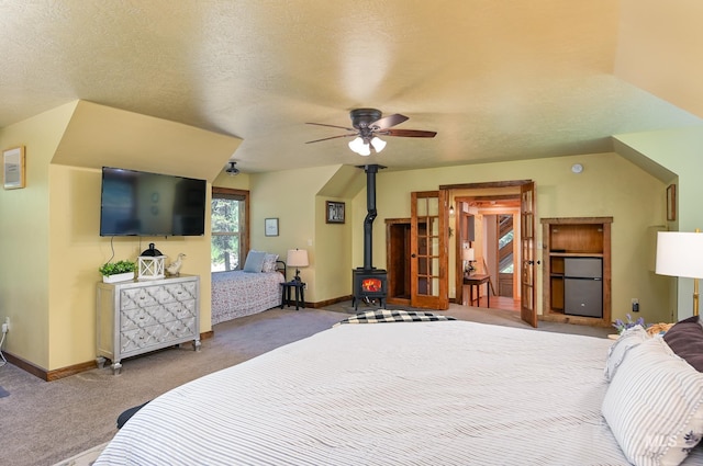 carpeted bedroom featuring a wood stove, fridge, baseboards, and a textured ceiling