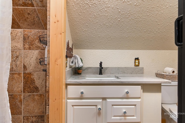 bathroom with a textured wall, a shower with curtain, and vanity