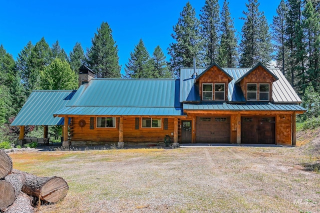 view of front facade featuring metal roof, a garage, dirt driveway, a standing seam roof, and a chimney