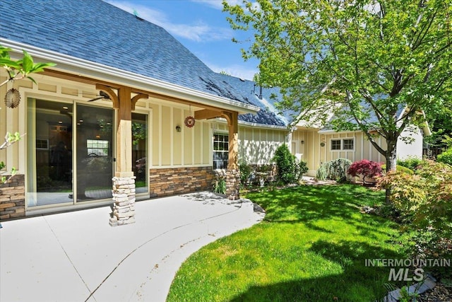 12970 N 9th Ave, Boise, ID 83714 - property entrance featuring board and batten siding, roof with shingles, a yard, stone siding, and a patio area