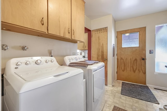 washroom featuring cabinets, washing machine and clothes dryer, and a healthy amount of sunlight