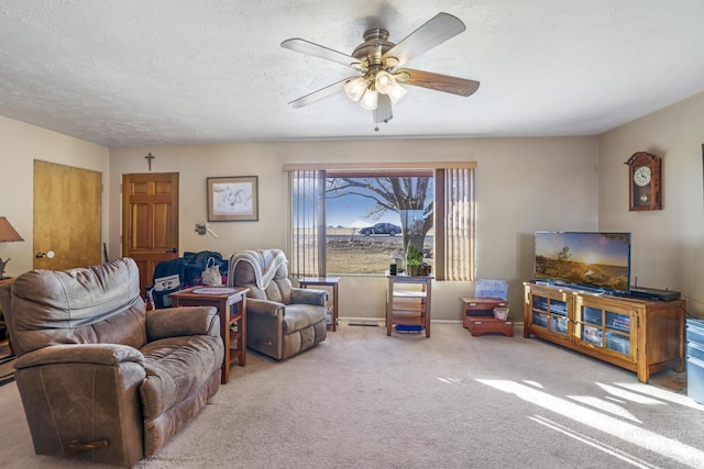 living room featuring ceiling fan, carpet floors, and a textured ceiling