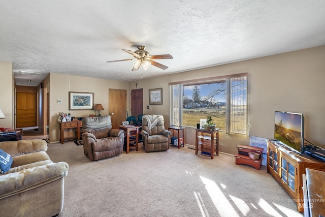 carpeted living room featuring ceiling fan and a textured ceiling