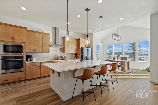 8237 W Corinthia St, Eagle, ID 83616 - kitchen with stainless steel appliances, wall chimney exhaust hood, light countertops, tasteful backsplash, and a center island with sink