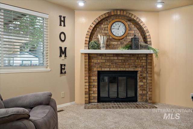 carpeted living room featuring wood walls and a fireplace