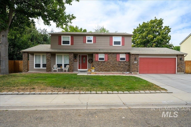 traditional home featuring brick siding, concrete driveway, fence, a garage, and a front lawn