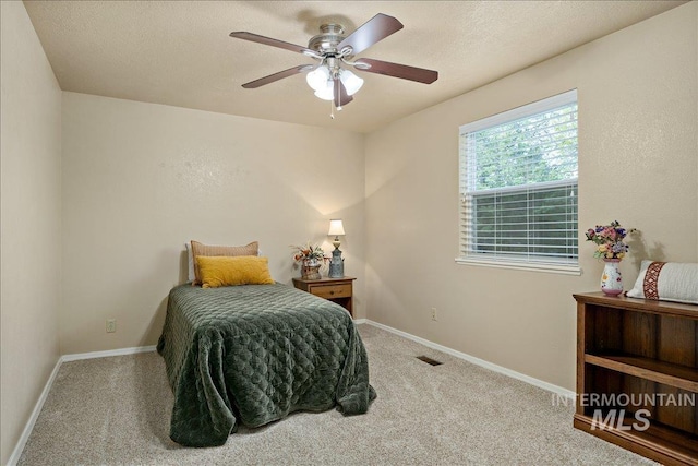 bedroom featuring a textured ceiling, carpet floors, a ceiling fan, visible vents, and baseboards