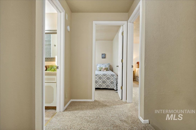 corridor with a textured wall, carpet flooring, and baseboards