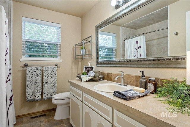 bathroom with visible vents, toilet, a shower with curtain, stone finish flooring, and vanity