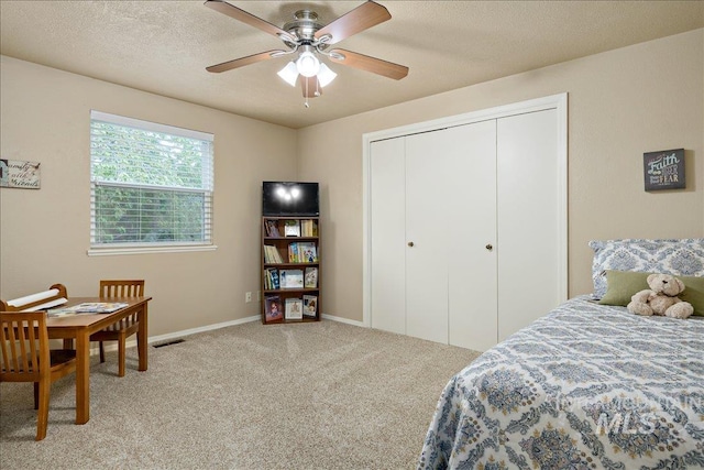 carpeted bedroom with a closet, visible vents, ceiling fan, a textured ceiling, and baseboards