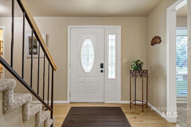 foyer featuring light wood-type flooring, stairs, and baseboards