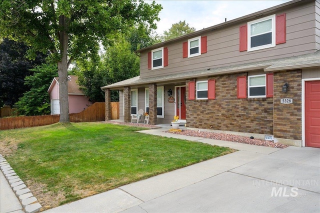 view of front of property featuring a garage, covered porch, brick siding, fence, and a front yard