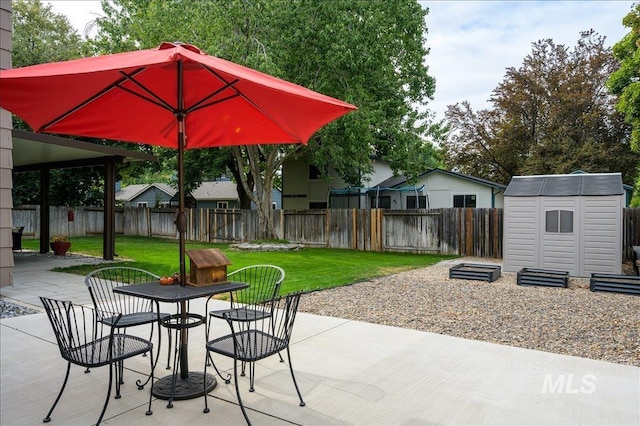 view of patio / terrace featuring an outbuilding, outdoor dining area, fence, and a storage unit