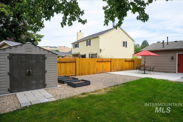 back of house with a fenced backyard, an outdoor structure, a lawn, a shed, and a patio area