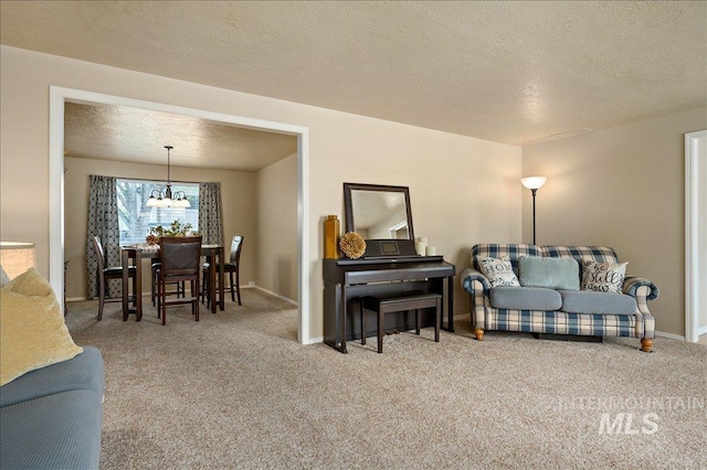 living area featuring a textured ceiling, baseboards, carpet flooring, and a notable chandelier