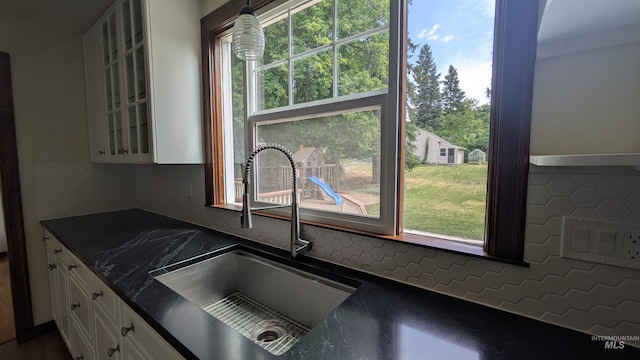 815 E 6th, Moscow, ID 83843 - kitchen with dark countertops, white cabinetry, glass insert cabinets, backsplash, and healthy amount of natural light