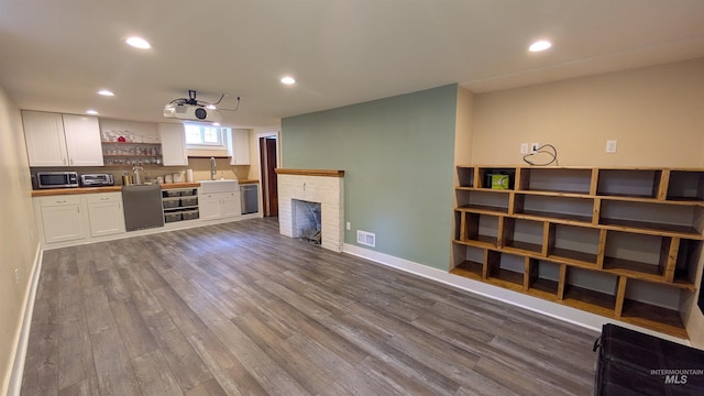 815 E 6th, Moscow, ID 83843 - unfurnished living room featuring wet bar, dark wood-style floors, recessed lighting, and a brick fireplace