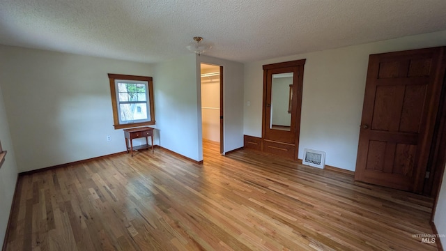 815 E 6th, Moscow, ID 83843 - unfurnished bedroom with light wood-style floors, a spacious closet, a textured ceiling, and a closet