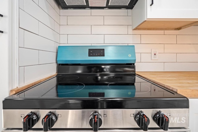 kitchen with stainless steel electric range, ventilation hood, decorative backsplash, white cabinets, and butcher block counters