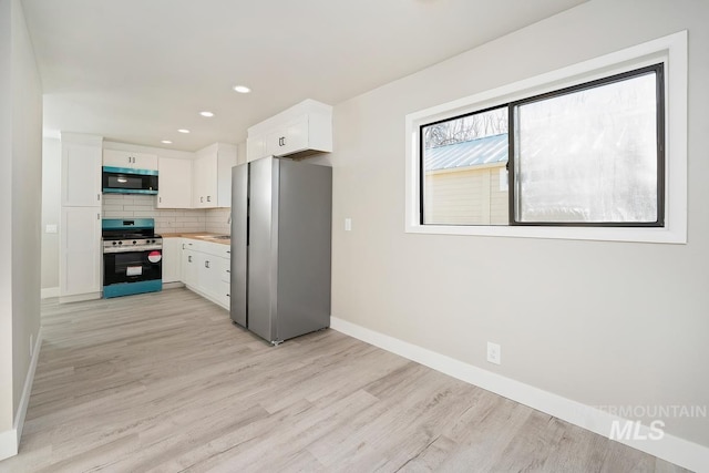 kitchen featuring white cabinets, stainless steel appliances, light hardwood / wood-style floors, and decorative backsplash