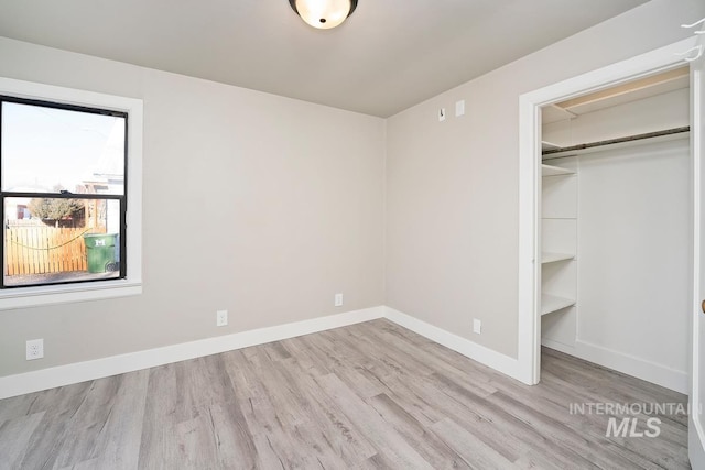 unfurnished bedroom with a walk in closet, a closet, and light hardwood / wood-style floors