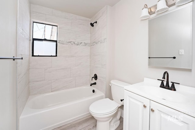 full bathroom featuring hardwood / wood-style floors, tiled shower / bath combo, vanity, and toilet