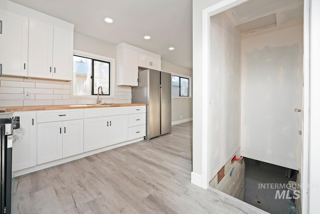 kitchen featuring white cabinets, butcher block counters, and sink