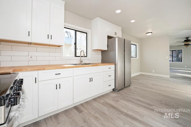 kitchen featuring sink, white cabinets, tasteful backsplash, and butcher block counters