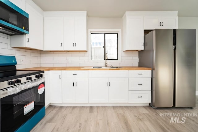 kitchen with wooden counters, stainless steel appliances, and white cabinets