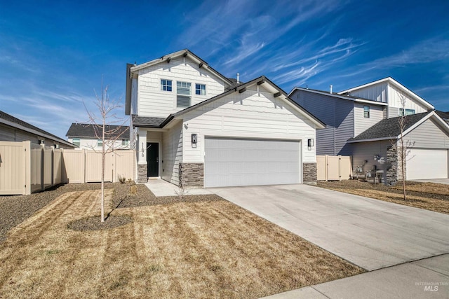 traditional home with stone siding, an attached garage, concrete driveway, and fence