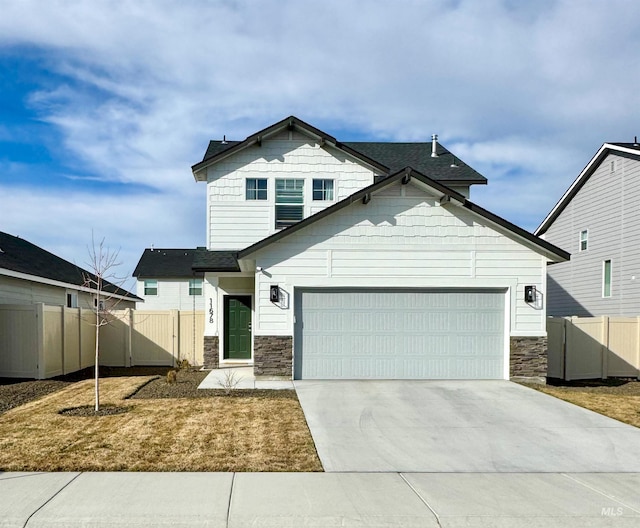 view of front facade featuring stone siding, fence, an attached garage, and driveway