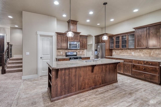 13569 Paoletti St, Caldwell, ID 83607 - kitchen featuring stainless steel appliances, light carpet, backsplash, a center island with sink, and recessed lighting