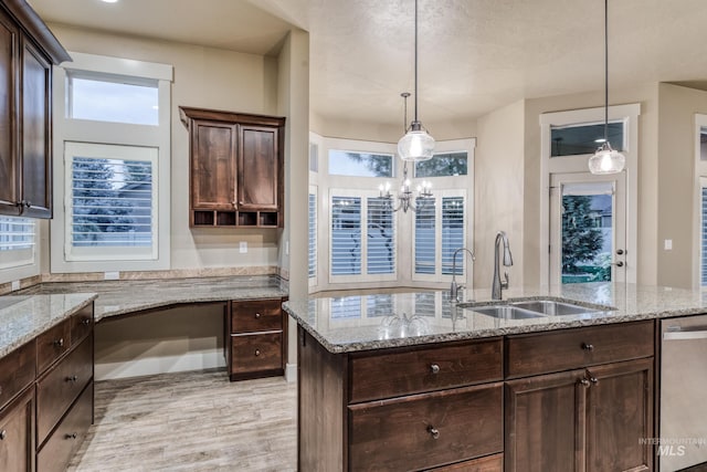 13569 Paoletti St, Caldwell, ID 83607 - kitchen with stainless steel dishwasher, dark brown cabinetry, light wood finished floors, and an island with sink