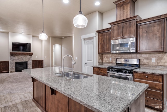 13569 Paoletti St, Caldwell, ID 83607 - kitchen featuring appliances with stainless steel finishes, a center island with sink, open floor plan, arched walkways, and backsplash