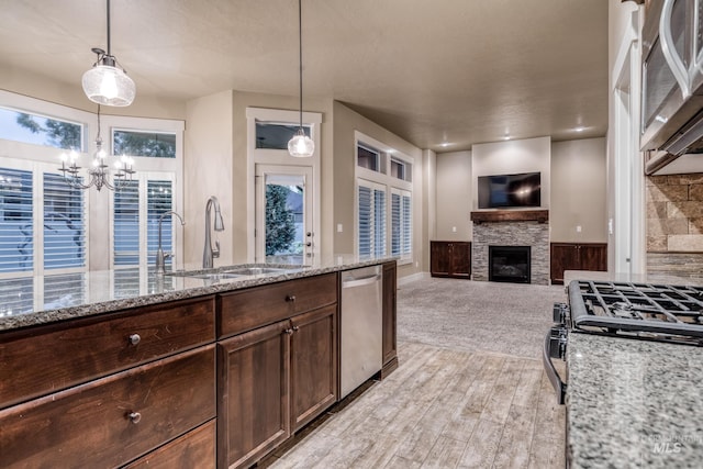 13569 Paoletti St, Caldwell, ID 83607 - kitchen featuring stainless steel appliances, a stone fireplace, dark brown cabinetry, a chandelier, and hanging light fixtures