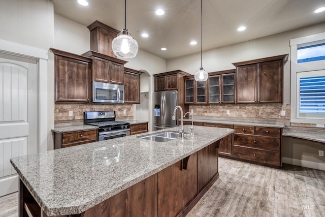 13569 Paoletti St, Caldwell, ID 83607 - kitchen with appliances with stainless steel finishes, light wood-style floors, arched walkways, decorative backsplash, and recessed lighting