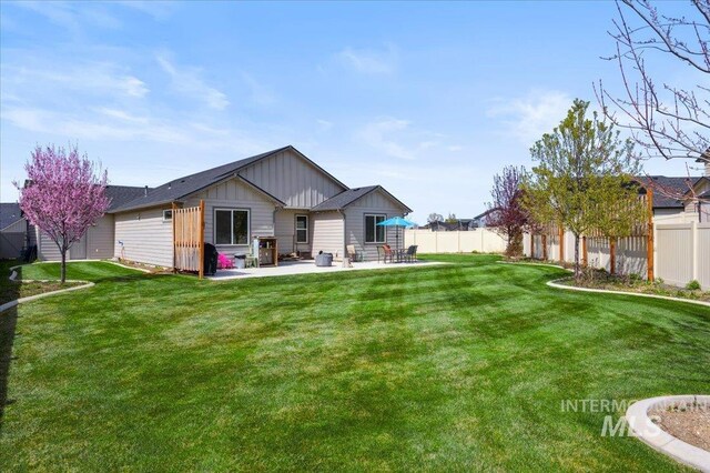 1046 N Warm River Ave, Kuna, ID 83634 - rear view of house with board and batten siding, a fenced backyard, a patio area, and a lawn