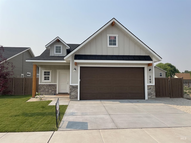 view of front facade featuring roof with shingles, concrete driveway, board and batten siding, a front yard, and fence