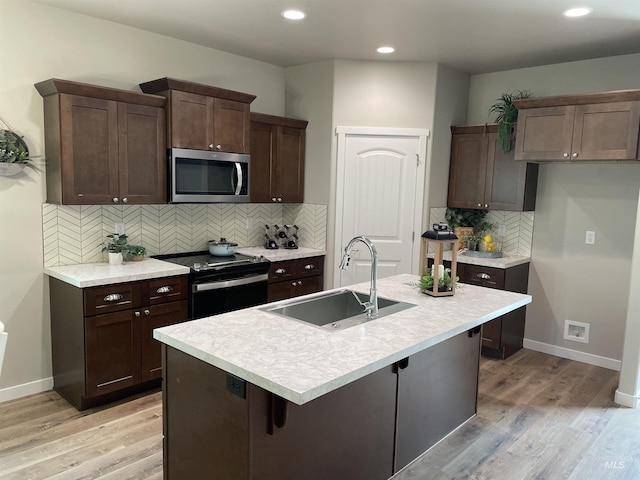 kitchen with light wood finished floors, electric range, stainless steel microwave, and a sink