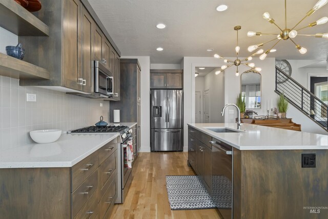 10110 Irongate Dr, Nampa, ID 83687 - kitchen featuring an island with sink, open shelves, a sink, decorative backsplash, and appliances with stainless steel finishes