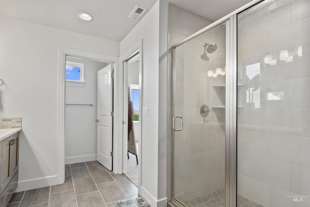 10110 Irongate Dr, Nampa, ID 83687 - full bathroom featuring baseboards, vanity, visible vents, and a shower stall