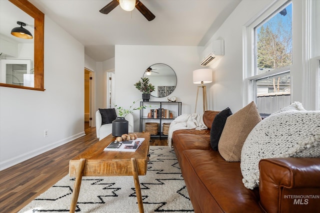 living room with baseboards, a wall mounted air conditioner, ceiling fan, and wood finished floors