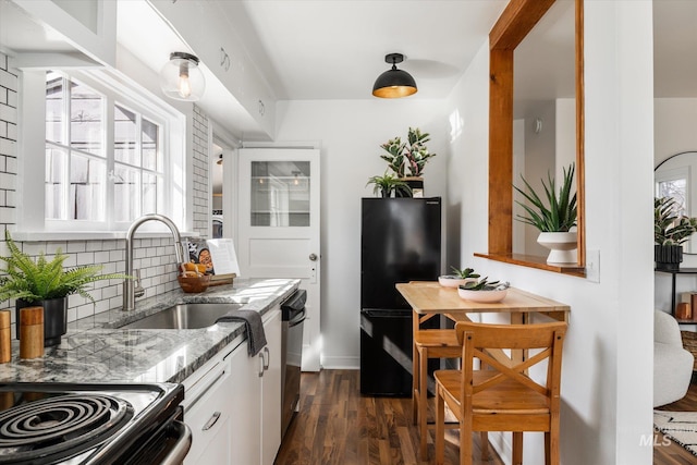 kitchen with dark wood-type flooring, decorative backsplash, freestanding refrigerator, stone countertops, and a sink