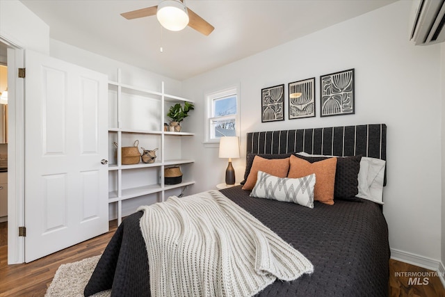 bedroom featuring ceiling fan, wood finished floors, and a wall unit AC