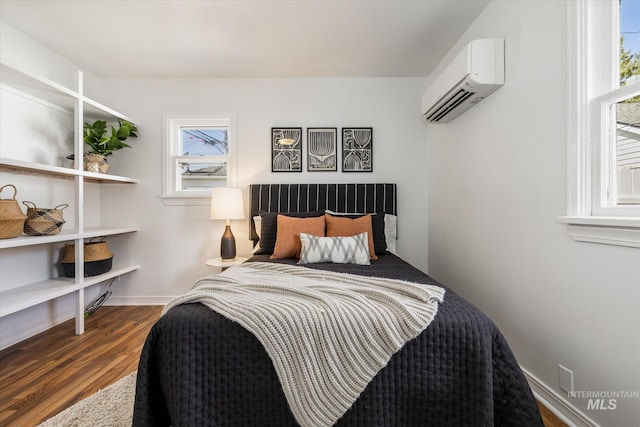 bedroom featuring a wall mounted air conditioner, baseboards, and dark wood-style floors