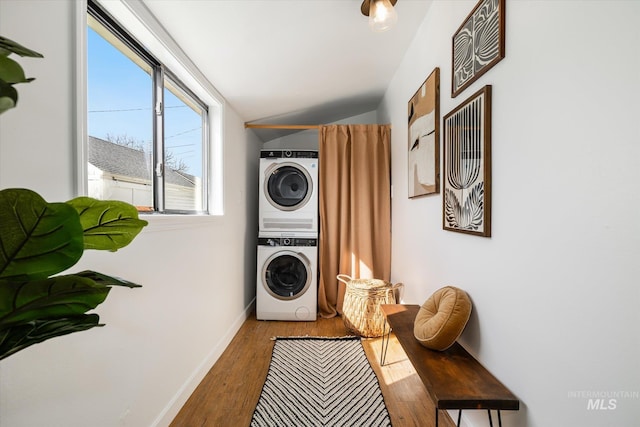 washroom with laundry area, stacked washer / drying machine, baseboards, and wood finished floors