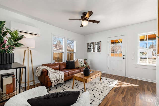 living room with a ceiling fan, an AC wall unit, wood finished floors, and baseboards