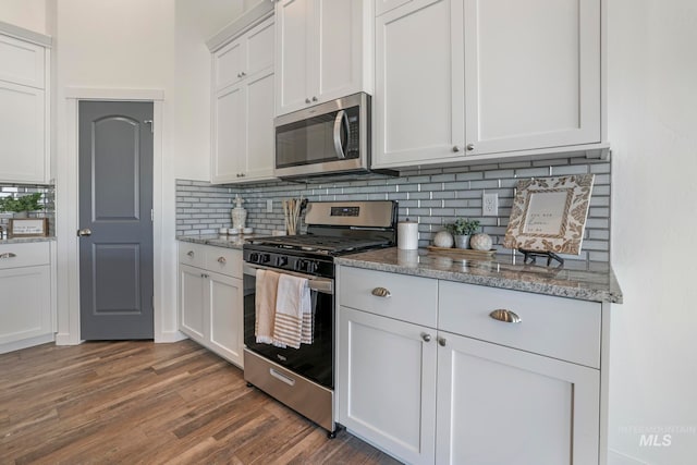 kitchen with light stone countertops, tasteful backsplash, stainless steel appliances, dark wood-type flooring, and white cabinetry