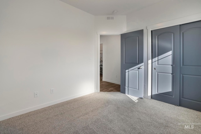 unfurnished bedroom with dark carpet and a closet