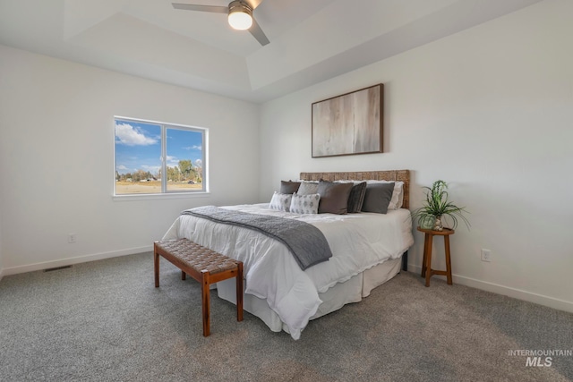 carpeted bedroom featuring ceiling fan and a raised ceiling